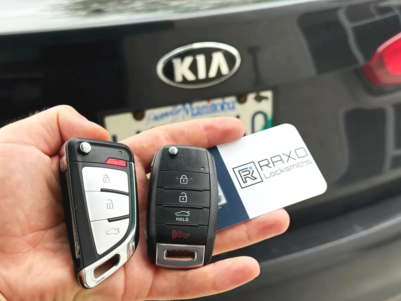 Two replacement Kia keys — a flip key and a Kia remote — cut and programmed at the customer's Kia in Winnipeg, RAXO card on the tailgate