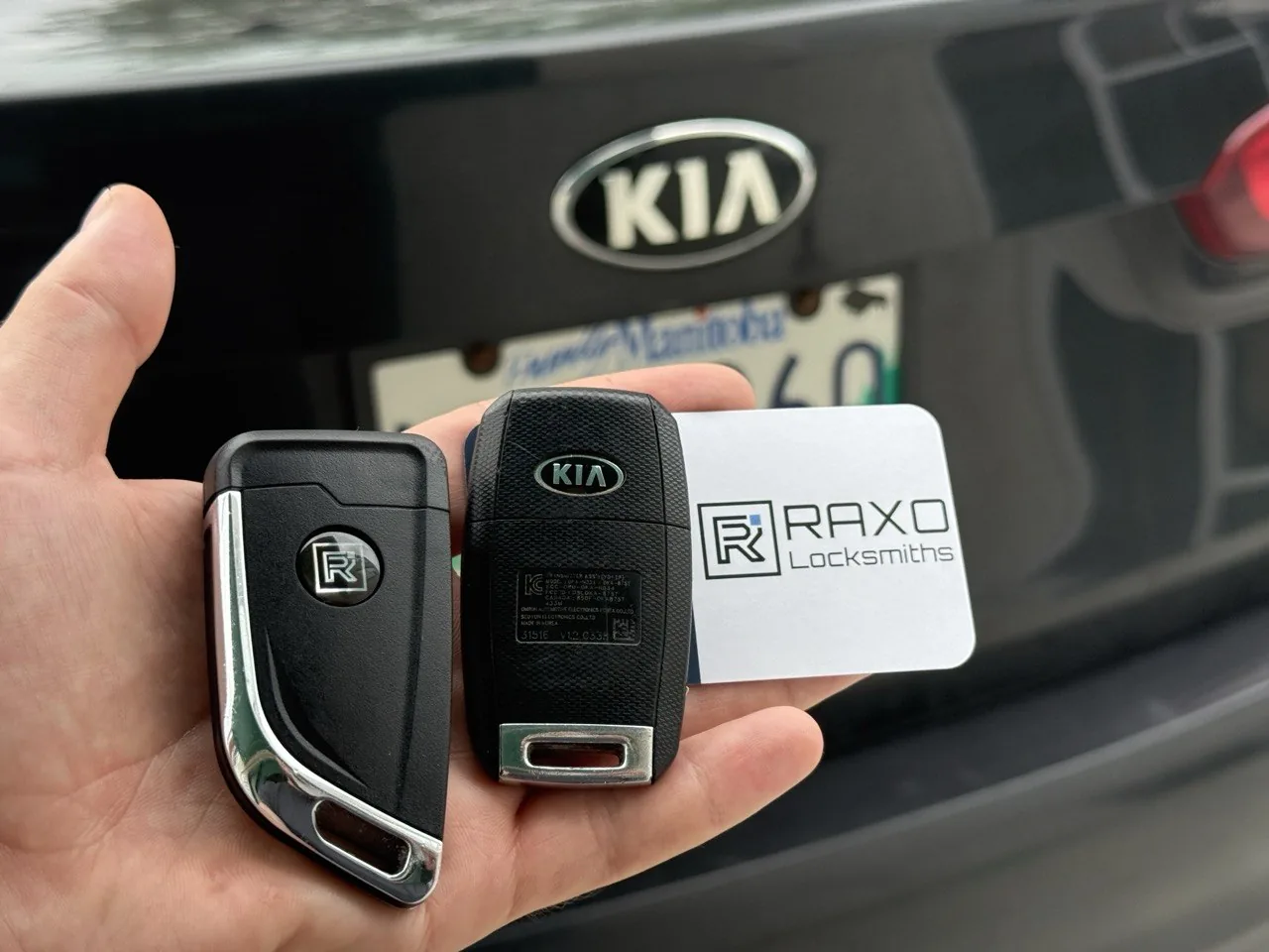 A new Kia flip key and a Kia remote key held at the Kia tailgate badge — programmed on-site by RAXO Locksmiths