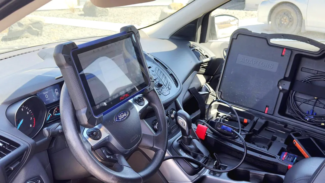 Leo's mobile locksmith setup on a Winnipeg job — a diagnostic tablet mounted at the steering wheel and an open case of key-programming adaptors on the seat