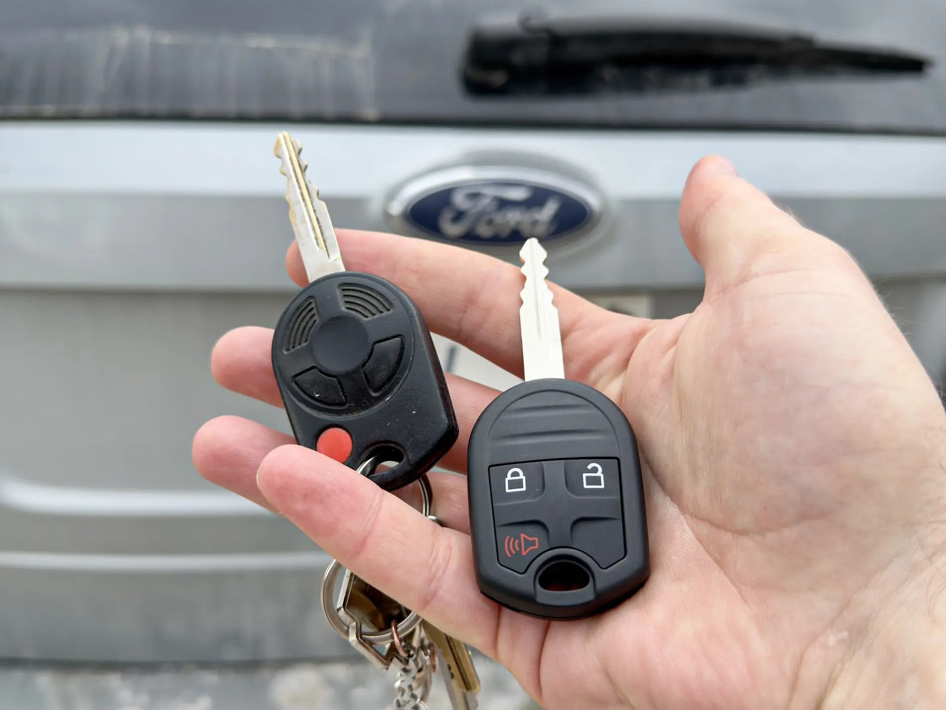 Freshly cut F-150 Intelligent Access Smart Key in hand, blue or red F-150 visible in background