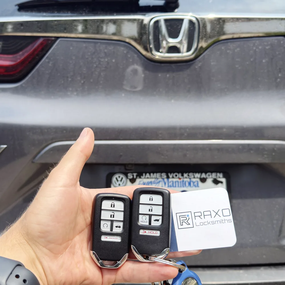 A new spare smart key beside the original for a 2022 Honda CR-V, programmed at the vehicle in Winnipeg, RAXO card at the tailgate