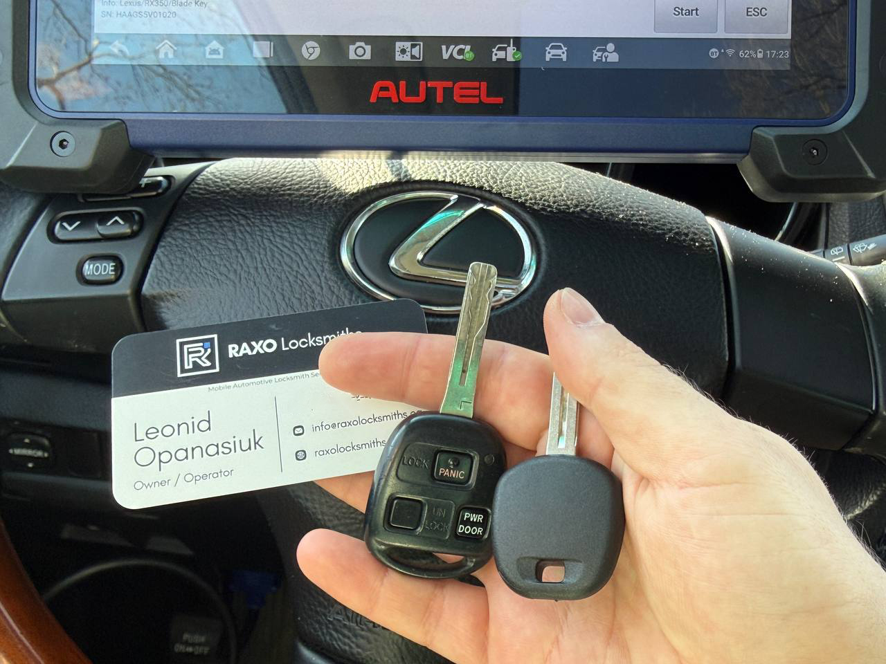 Freshly cut Toyota laser-cut Smart Key in hand, RAV4 or Camry visible in background